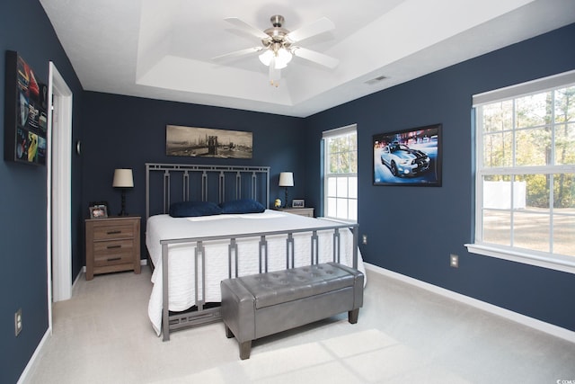 bedroom with baseboards, a raised ceiling, light carpet, and visible vents