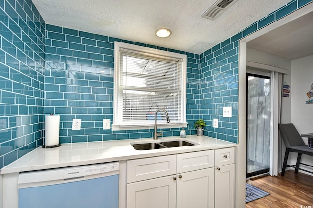 kitchen with sink, white cabinetry, dishwasher, light hardwood / wood-style floors, and backsplash