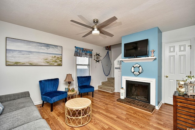 living room with a fireplace, light hardwood / wood-style flooring, and a textured ceiling