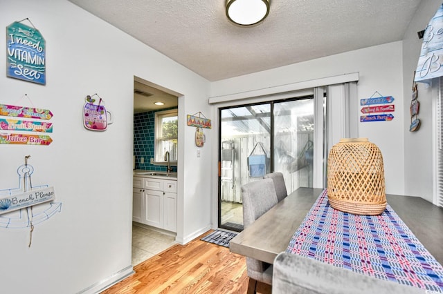 dining space featuring sink, light hardwood / wood-style floors, and a textured ceiling