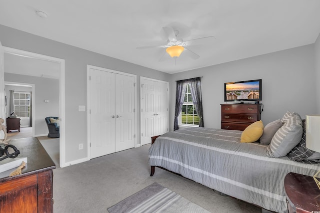 bedroom featuring two closets, carpet, a ceiling fan, and baseboards
