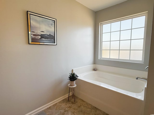 full bath with tile patterned flooring, a garden tub, and baseboards