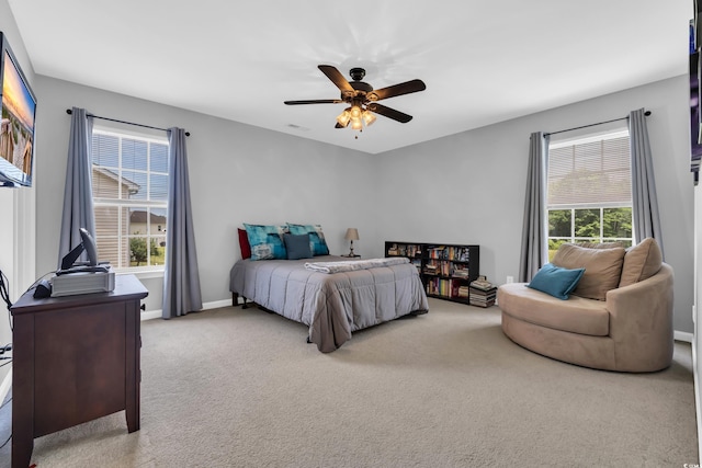 carpeted bedroom with multiple windows, ceiling fan, and baseboards
