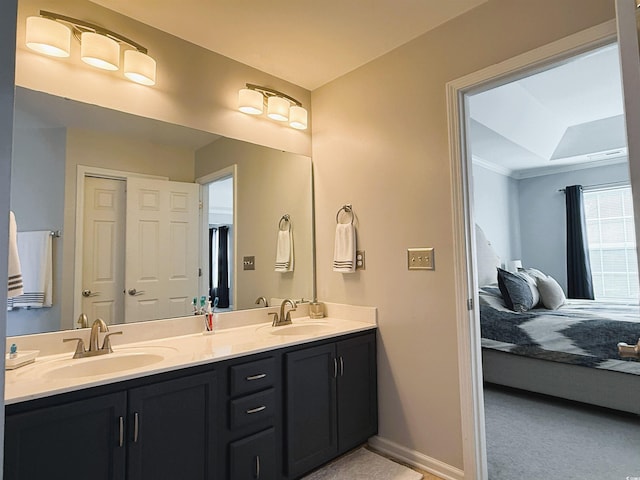 bathroom featuring double vanity, ensuite bath, a sink, and baseboards