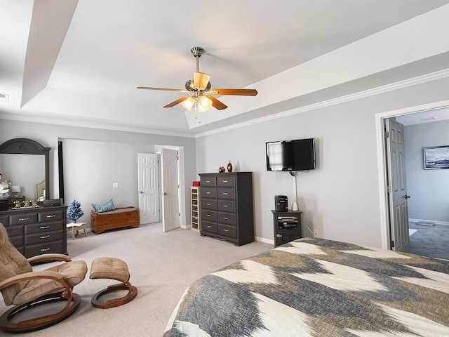 bedroom with ceiling fan, connected bathroom, a raised ceiling, light colored carpet, and crown molding