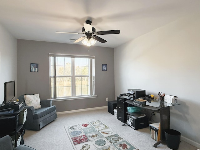 home office featuring light carpet, a ceiling fan, and baseboards