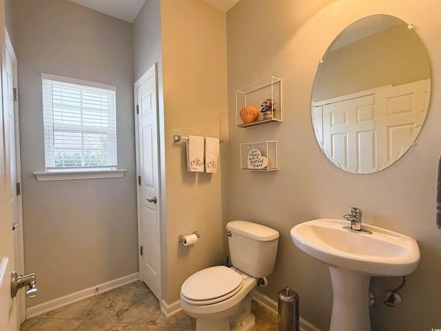 half bathroom featuring baseboards, a sink, and toilet