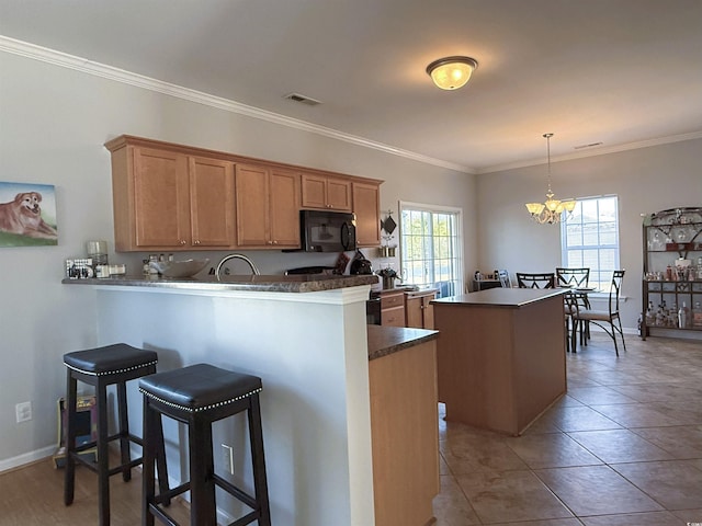 kitchen featuring kitchen peninsula, crown molding, hanging light fixtures, a kitchen breakfast bar, and a chandelier