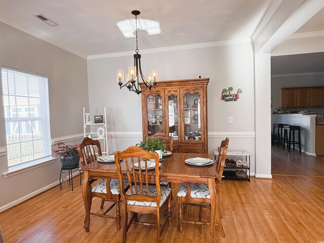 dining room with light hardwood / wood-style floors, a chandelier, and ornamental molding