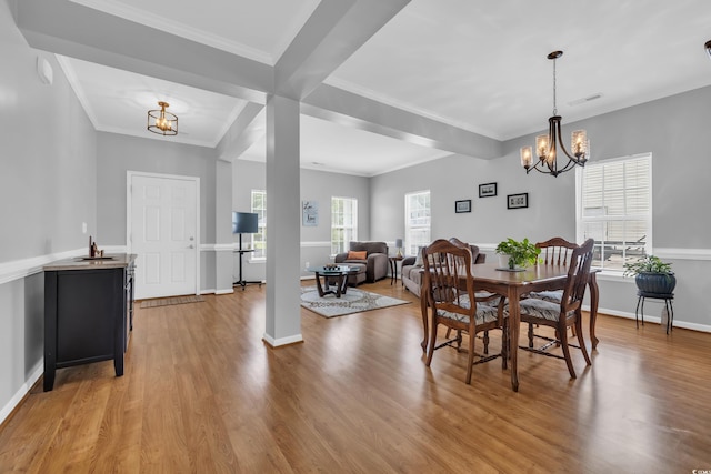 dining room with a chandelier, wood finished floors, baseboards, and ornamental molding