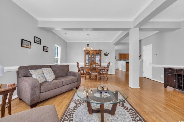 living area featuring light wood finished floors, a chandelier, baseboards, and crown molding