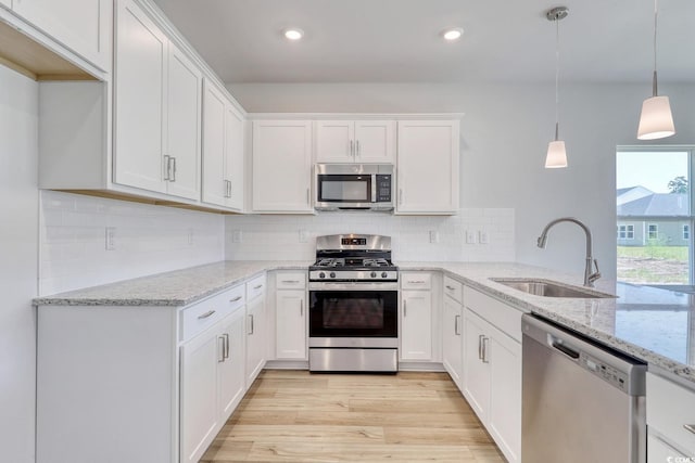 kitchen featuring sink, pendant lighting, appliances with stainless steel finishes, and white cabinets