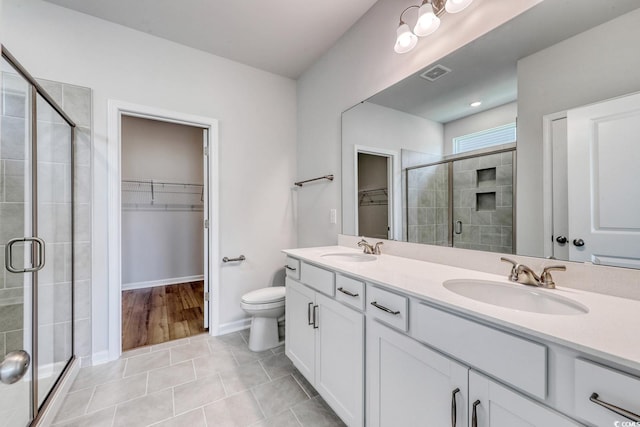 bathroom featuring a shower with shower door, vanity, tile patterned flooring, and toilet