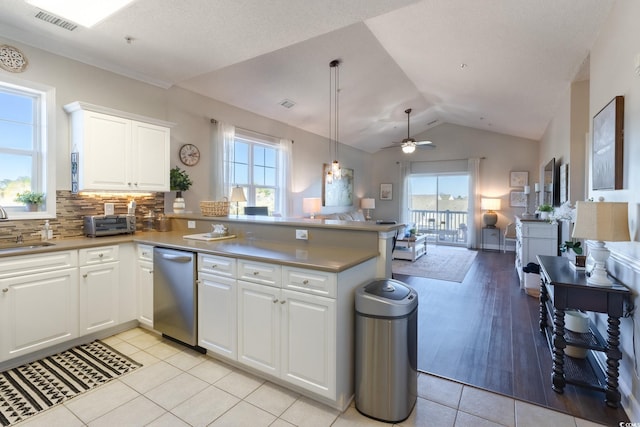 kitchen featuring visible vents, a sink, open floor plan, a peninsula, and dishwasher