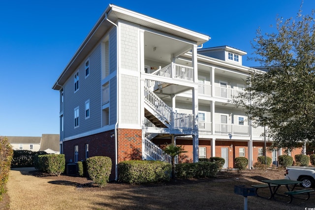 view of home's exterior featuring cooling unit, brick siding, and stairway