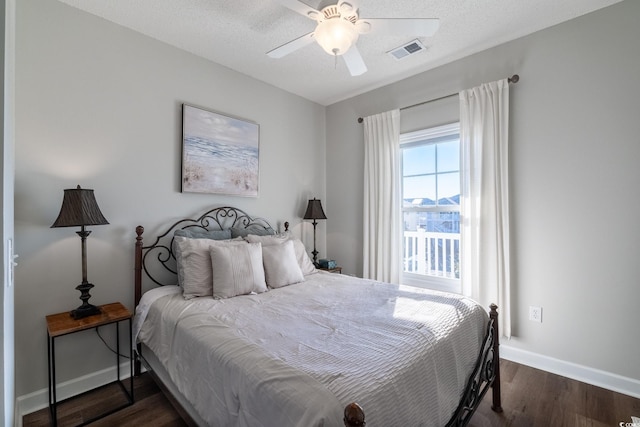 bedroom featuring visible vents, baseboards, a textured ceiling, a ceiling fan, and dark wood-style flooring