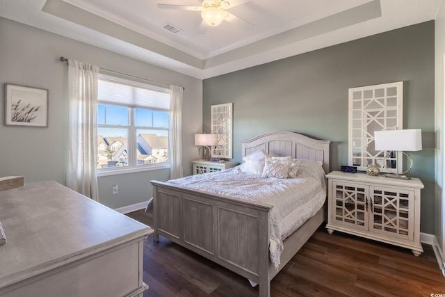 bedroom with visible vents, a raised ceiling, and dark wood-style flooring