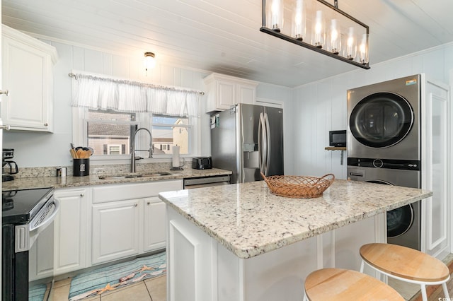 kitchen featuring stacked washer and dryer, appliances with stainless steel finishes, and white cabinetry