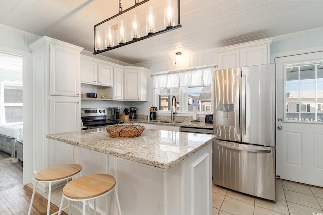 kitchen featuring a center island, decorative light fixtures, white cabinetry, stainless steel appliances, and sink