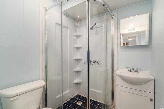 bathroom featuring toilet, tile patterned flooring, a shower with door, and vanity