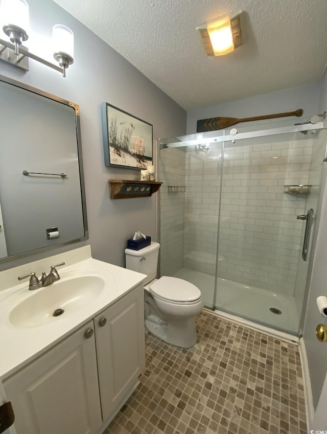 bathroom with an enclosed shower, vanity, a textured ceiling, and toilet