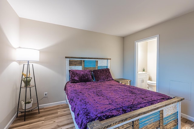 bedroom with connected bathroom, light wood-style flooring, and baseboards