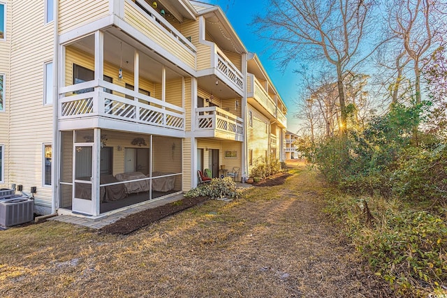rear view of house featuring a sunroom, a balcony, and central air condition unit