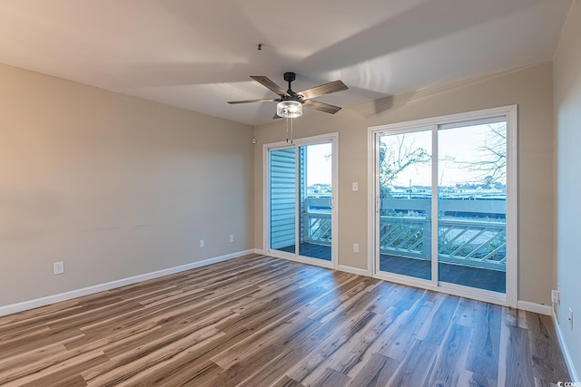 unfurnished room featuring baseboards, wood finished floors, and a ceiling fan