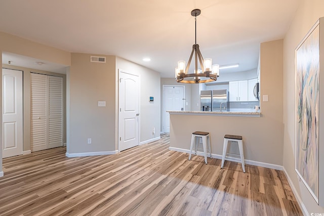 kitchen featuring visible vents, baseboards, light wood-style flooring, appliances with stainless steel finishes, and a breakfast bar area