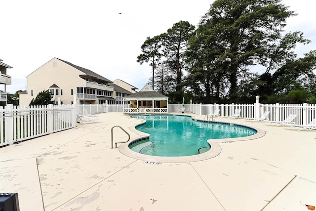 pool featuring an outbuilding, a patio area, and fence