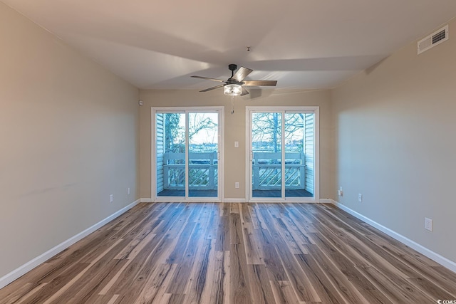 spare room with a ceiling fan, visible vents, baseboards, and wood finished floors