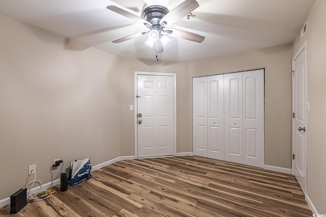 unfurnished bedroom with visible vents, wood finished floors, a closet, baseboards, and ceiling fan