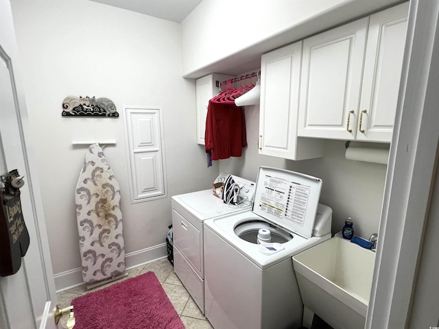 washroom with light tile patterned floors, sink, washer and clothes dryer, and cabinets