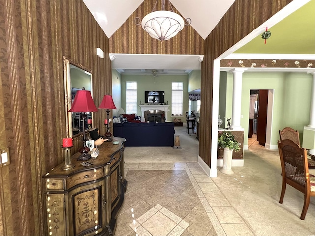 entrance foyer featuring decorative columns, ceiling fan, wooden walls, and vaulted ceiling