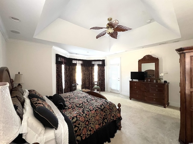 bedroom featuring ceiling fan, crown molding, a tray ceiling, and light carpet