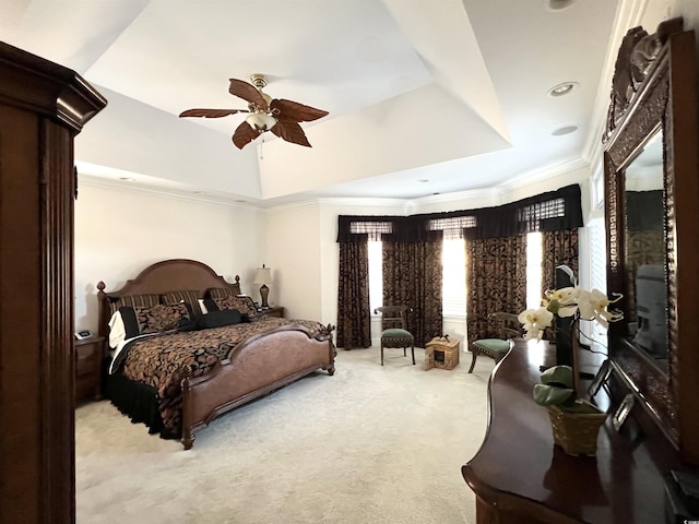 bedroom with ceiling fan, a raised ceiling, and light carpet