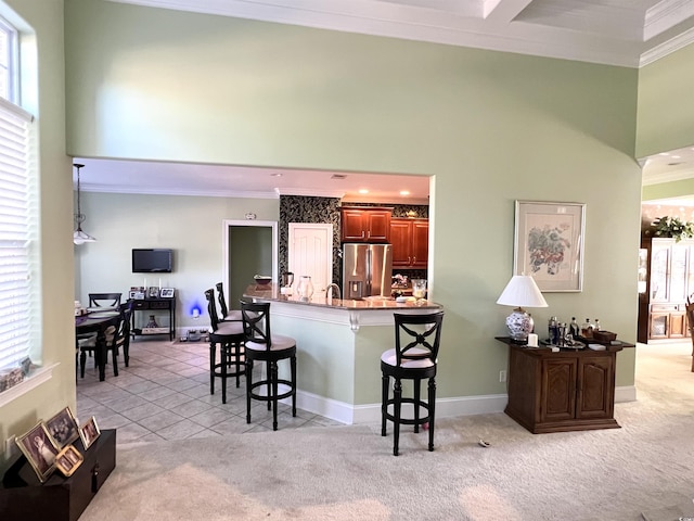 kitchen with kitchen peninsula, crown molding, light colored carpet, stainless steel fridge with ice dispenser, and a kitchen bar