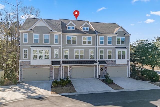 townhome / multi-family property with stone siding, concrete driveway, and a garage