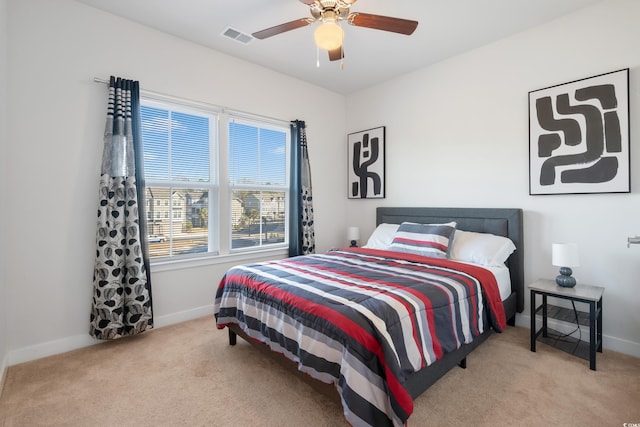 bedroom with light colored carpet, ceiling fan, visible vents, and baseboards