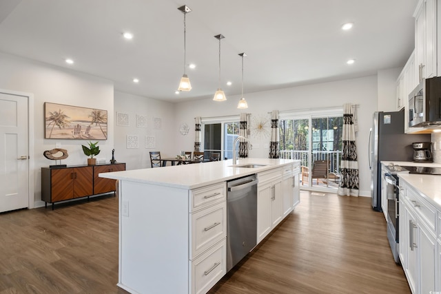 kitchen featuring stainless steel appliances, white cabinets, light countertops, and an island with sink