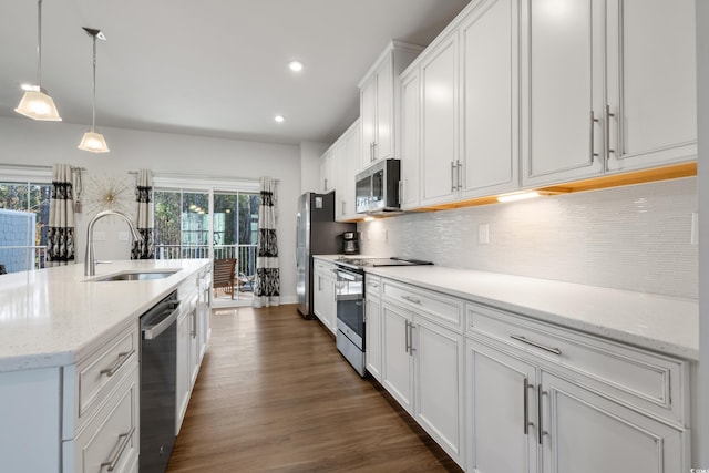 kitchen with tasteful backsplash, white cabinets, appliances with stainless steel finishes, pendant lighting, and a sink