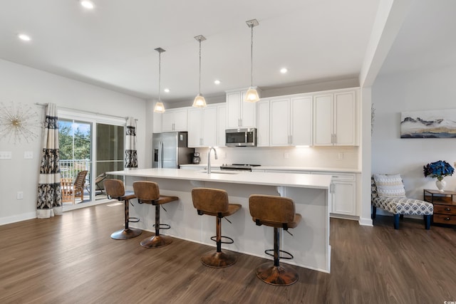 kitchen with stainless steel appliances, white cabinets, light countertops, an island with sink, and pendant lighting