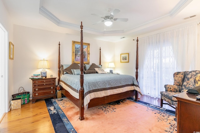 bedroom with ceiling fan, crown molding, light hardwood / wood-style flooring, and a raised ceiling