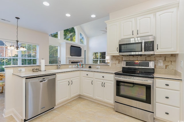 kitchen featuring appliances with stainless steel finishes, white cabinetry, sink, a notable chandelier, and vaulted ceiling