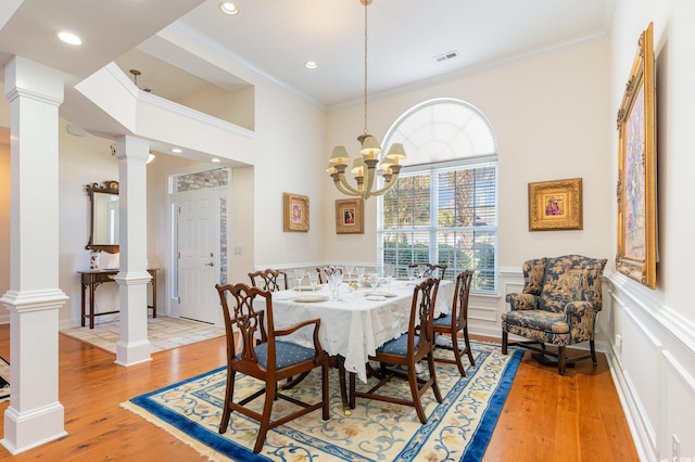 dining space with hardwood / wood-style flooring, ornamental molding, and a notable chandelier