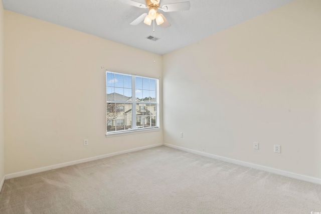 unfurnished room featuring light carpet, a ceiling fan, visible vents, and baseboards