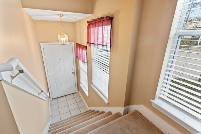 tiled foyer entrance with a chandelier, baseboards, and stairs