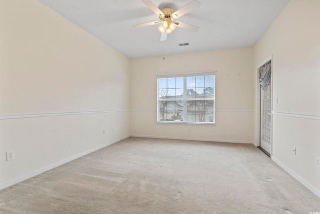 carpeted empty room with baseboards, visible vents, and ceiling fan