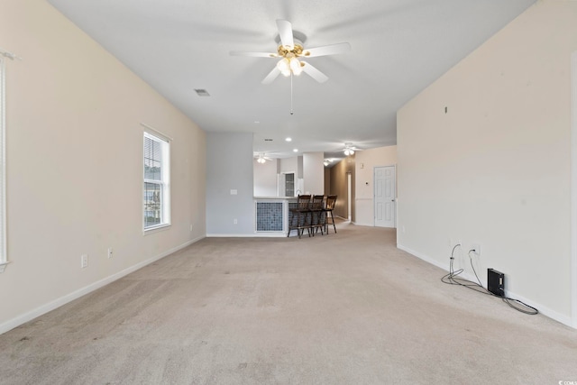 unfurnished living room with light carpet, baseboards, and a ceiling fan