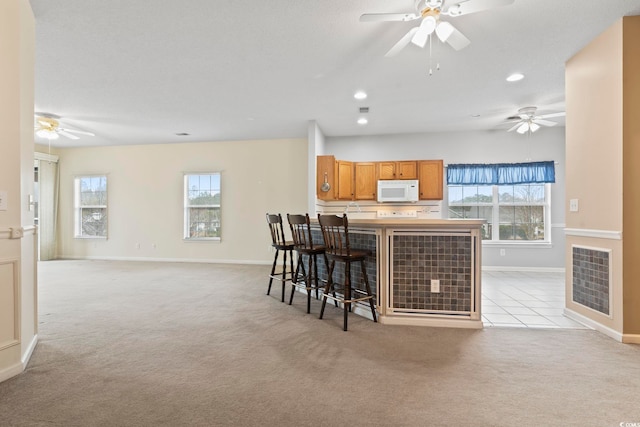 kitchen with recessed lighting, visible vents, white microwave, brown cabinetry, and light carpet